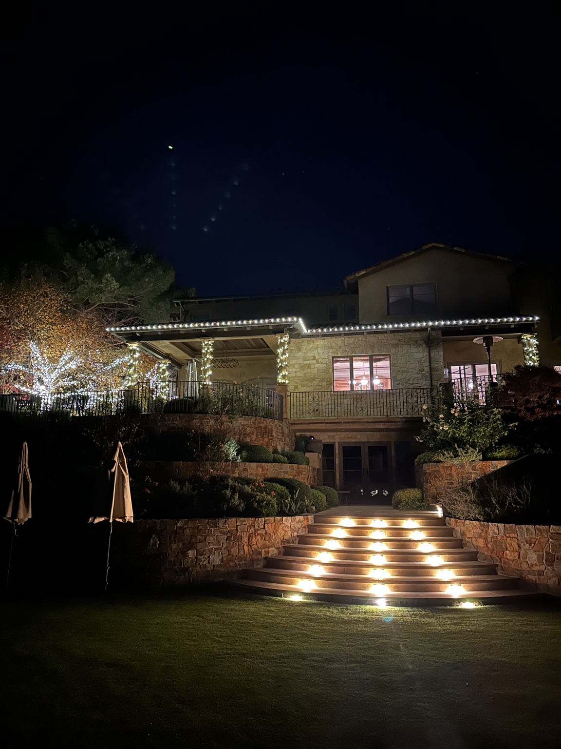 Mediterranean tile-roof estate with warm amber permanent roofline lighting at night