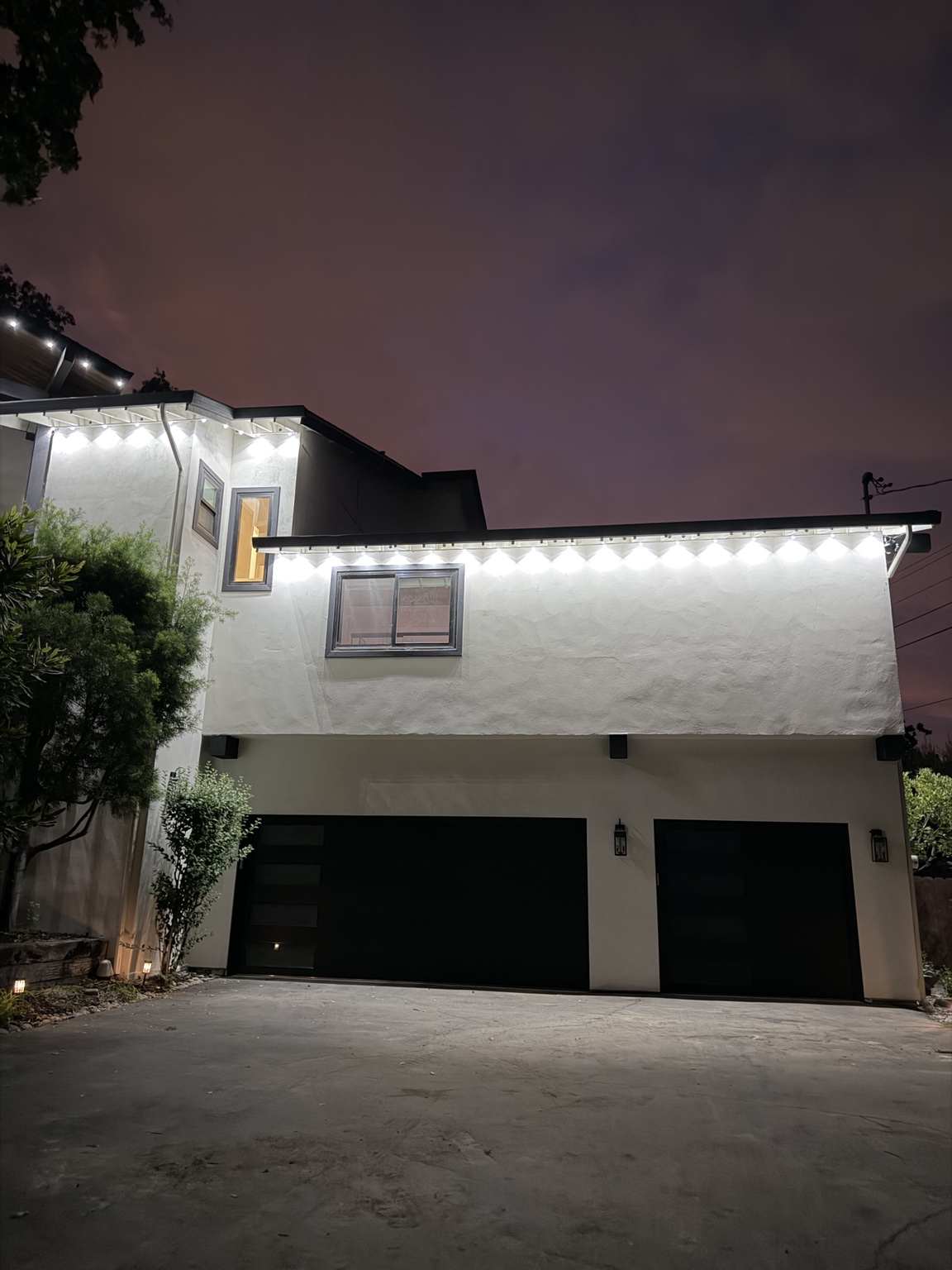 Nighttime view of a home with permanent roofline lighting illuminated